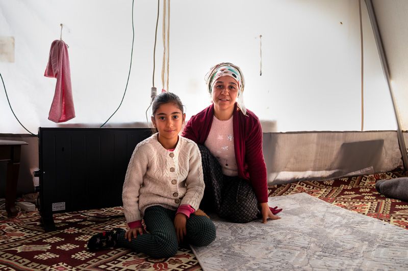 Yadigar*, 35 and Fidan*, 9 sit on the rugs the received with new electric heater. | Photo: Ayşe Nur Gençalp / Save the Children Türkiye