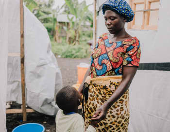 Esther*, 36 holds hands with Zawadi*, 4, outside the isolation tents | Photo: Hugh Kinsella Cunningham / Save the Children
