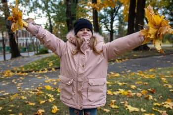 Emiliya, 7 years old plays in the autumn leaves in a park in Sumy, Ukraine| Photo: Sacha Myers / Save the Children