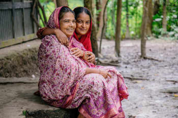 Bulu and Amina 18 sat on their porch at home in Barishal, Bangladesh. | Photo: Anna Sass / Save the Children