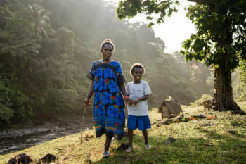 Sylvie, 8, and her mum Caroline, 33, walking through their village in Sanma Province, Vanuatu. | Photo: Conor Ashleigh / Save the Children
